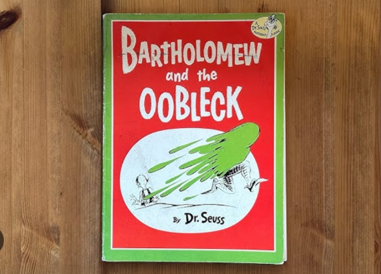 Image of Dr. Suess's book Bartholomew and the Oobleck laying on a wooden table.